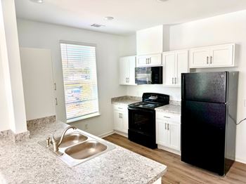 A kitchen with black appliances and white cabinets.